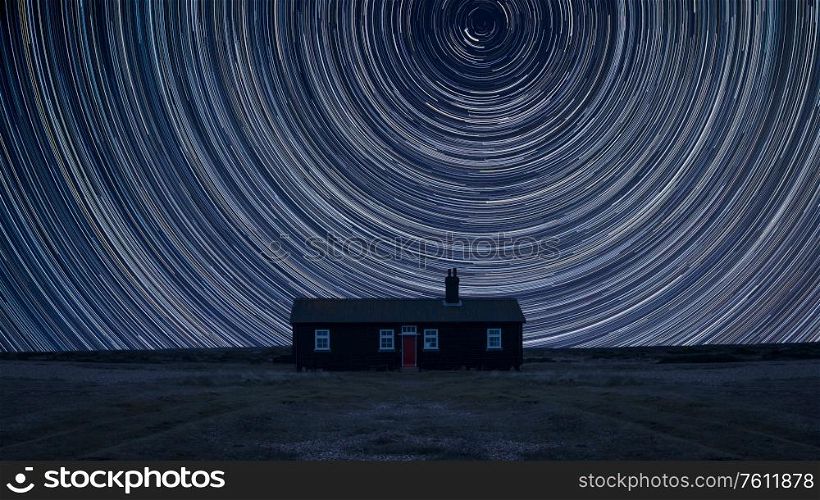 Digital composite image of star trails around Polaris with Stunning vibrant landscape of Remote desolate isolated house