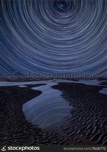 Digital composite image of star trails around Polaris with Stunning vibrant landscape of Beautiful Summer golden beach
