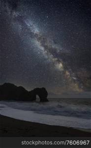 Digital composite of Milky Way over epic seascape landscape image of cliffs and archway
