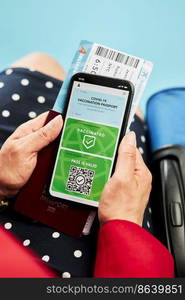 Digital covid certificate. Covid vaccination digital pass. Woman passenger holding digital medical pass on her mobile phone, passport and airplane ticket. Traveler showing digital covid test result as medical pass for travel during covid-19 pandemic