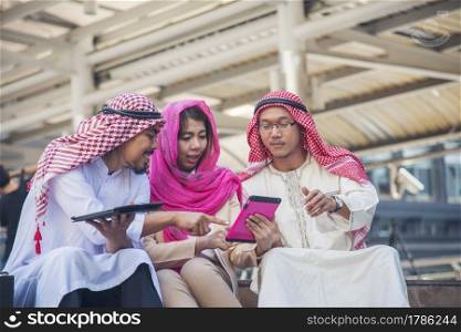 Digital marketing group arab people using smart tablet walking in  modern muslim UAE city touch screen discussion. Entrepreneur Asian people smile talking with boss outdoors