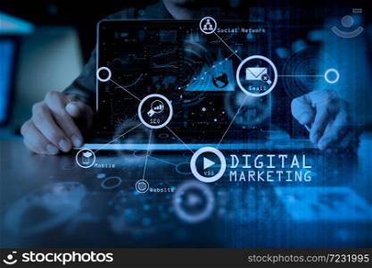 Digital marketing media (website ad, email, social network, SEO, video, mobile app) in virtual screen.business man hand working on laptop computer with digital layer business strategy and social media diagram on wooden desk.