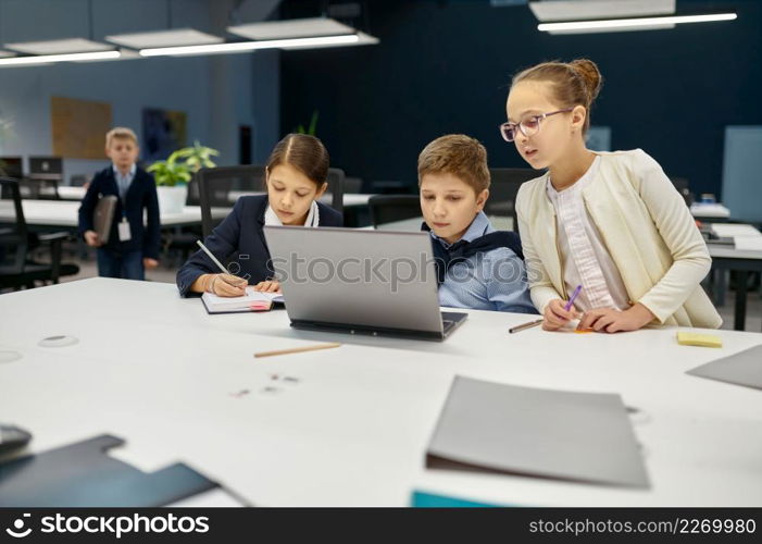 Digital native students e-learning over laptop computer. Busy kids business IT group sitting at desk. Digital native students e-learning over laptop computer