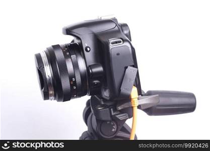 Digital photo camera on black tripod with orange cable.. Digital photo camera on black tripod with orange cable