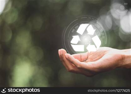 Digital recycling technology in men&rsquo;s hands against natural backgrounds.