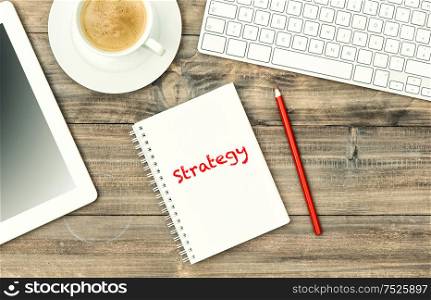 Digital tablet pc, keyboard and cup of coffee on wooden table. Home office workplace. Vintage style toned picture. Sample text Strategy