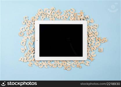 digital tablet with black display screen multiple wooden letters against blue background