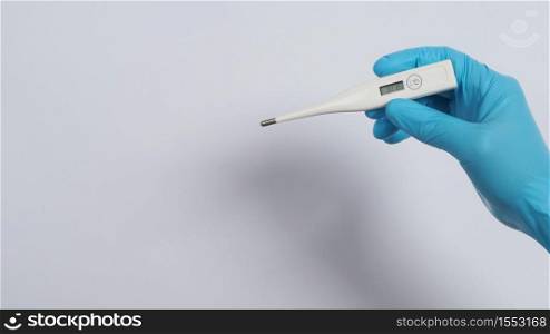 Digital thermometer white color in doctor hands wearing hospital medical gloves light blue color which can shown checking temperature numbers in celsius or fahrenheit degree for pandemic fever