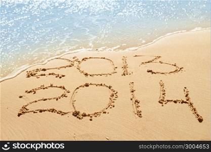 digits 2013 and 2014 on the sand seashore - concept of new year and passing of time