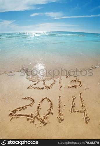 digits 2013 and 2014 on the sand seashore - concept of new year