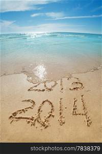 digits 2013 and 2014 on the sand seashore - concept of new year