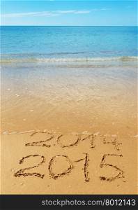 digits 2014 and 2015 on the seashore sand - concept of new year and passing of time