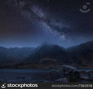 Digtial composite image of Winter landscape of snowcapped Mountain Range at night with Milky Way above