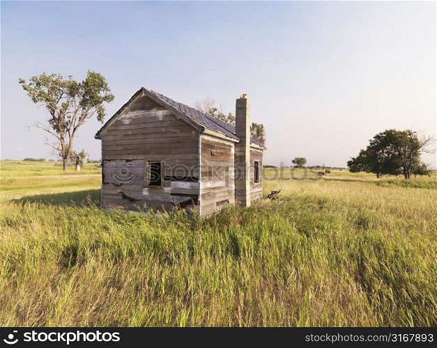 Dilapidated wooden house in rural field.