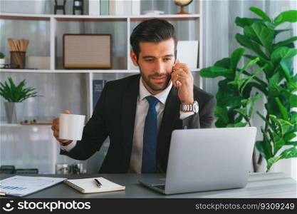 Diligent businessman busy talking on the phone call with clients while working with laptop in his office as concept of modern hardworking office worker lifestyle with mobile phone. Fervent. Businessman making a sales call with clients at office. fervent