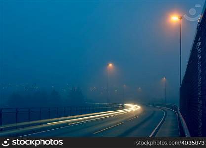 Diminishing perspective of light trails on misty road illuminated by street lights, Haugesund, Rogaland County, Norway