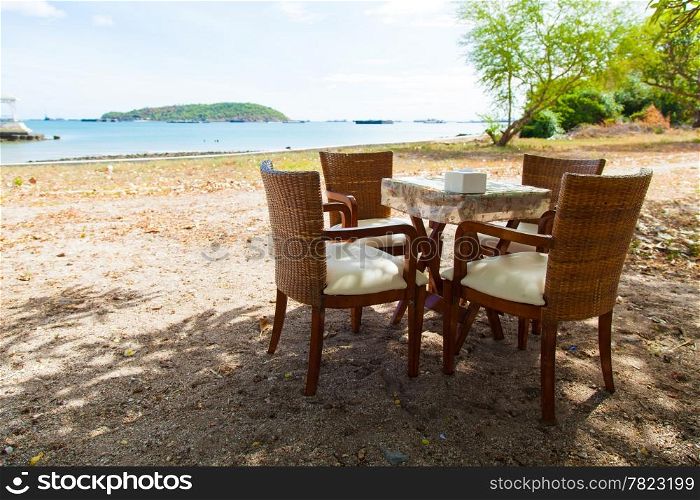Dining Table and umbrella. Under a tree in a seaside restaurant. Cloudy atmosphere.