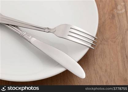 Dining table with fork and knife on white plate on wooden table