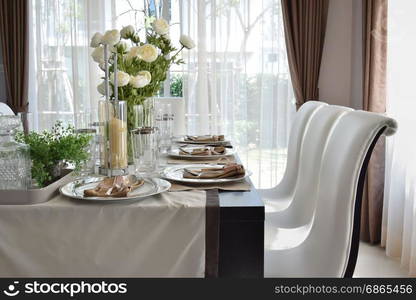 dining wooden table and comfortable chairs in modern home with elegant table setting