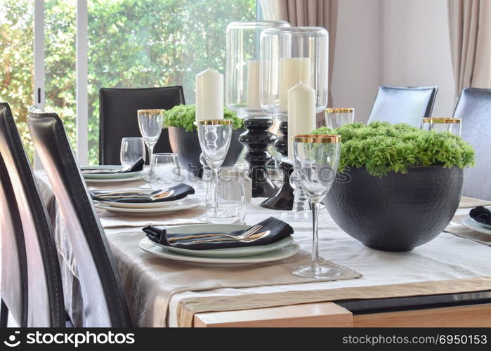 dining wooden table and comfortable chairs in modern home with elegant table setting