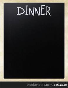 ""Dinner" handwritten with white chalk on a blackboard"
