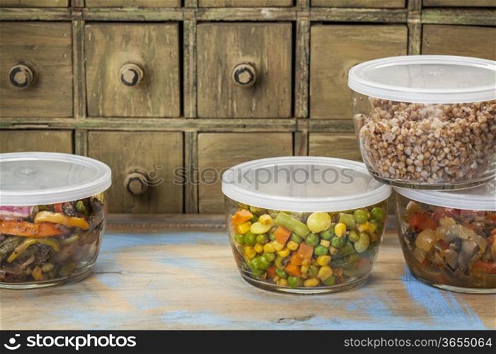 dinner leftovers (buckwheat kasha, vegetables, stir fry) in glass containers with drawer cabinet in background