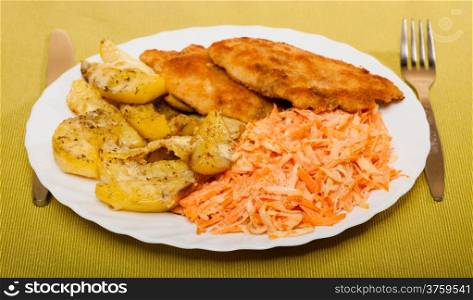 Dinner meal. Fried chicken roasted potatos with cheese and vegetables carrot salad on plate.
