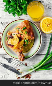 Dinner of baked chicken thighs in orange with spices. drumstick on porcelain plate