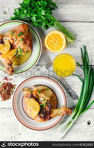 Dinner of baked chicken thighs in orange with spices. drumstick on porcelain plate