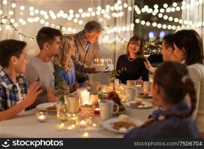 dinner party and celebration concept - happy family with cake celebrating grandmothers birthday at home. happy family having birthday party at home