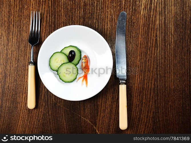 dinner setting dish on wooden table. fork and plate with golfish and salad
