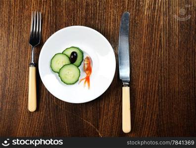 dinner setting dish on wooden table. fork and plate with golfish and salad