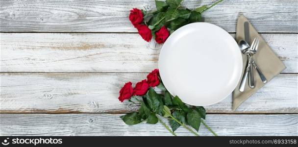 Dinner setting with red roses on rustic white wood in flat lay view for Valentine holiday