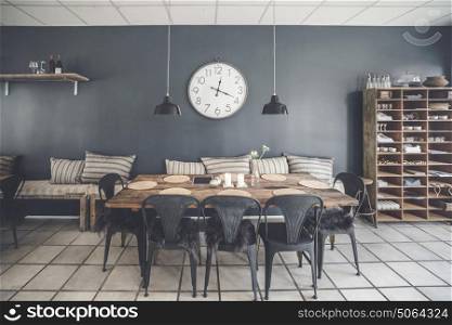 Dinner table in a retro living room with furniture made of wood and a big clock hanging on the wall