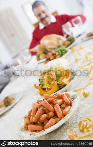 Dinner Table With Christmas Dishes,With Man In Background Carving Turkey