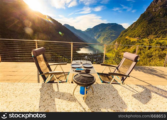 Dinner table with grill outdoor in norwegian mountains with view over Geiranger fjord. Traveling, camping on nature.. Dinner table with grill on norwegian nature