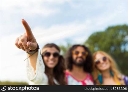 direction, gesture and people concept - hippie woman with friends pointing finger outdoors. happy hippie woman pointing finger outdoors