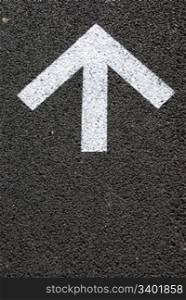 directional white arrow sign on the asphalt road