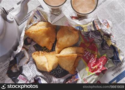 Directly above shot of fresh samosas with tea glasses on table