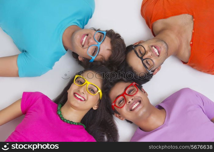 Directly above shot of friends lying with their heads together on white background