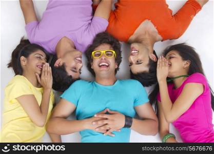 Directly above shot of friends sharing secret while lying on studio