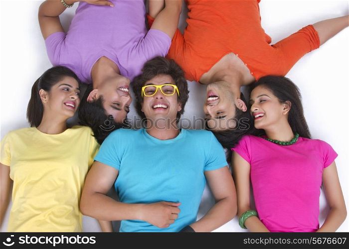 Directly above shot of young friends sharing secret while lying over white background
