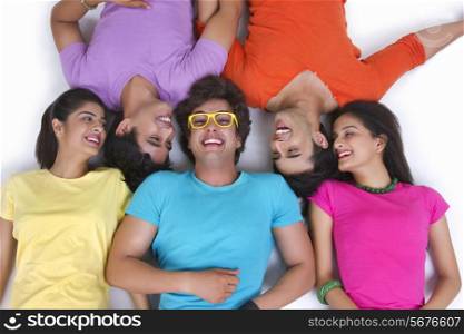 Directly above shot of young friends sharing secret while lying over white background