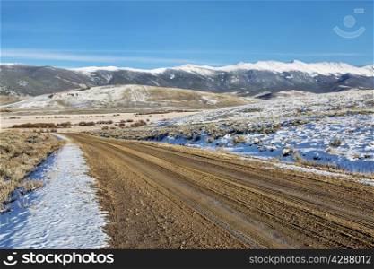 dirt backcountry road with snowy Medicine Bow Mountains in background, North Park near Walden, Colorado, late fall scenery