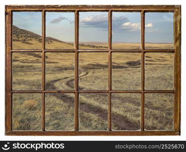 dirt ranch road in prairie in northern Colorado, early spring scenery as seen from a vintage sash window