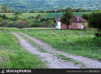 Dirt road and abandoned house in Bulgaria in the spring