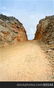 Dirt road dug in the hill in the mountains . Dirt road dug in the hill in the mountains on the island of Crete