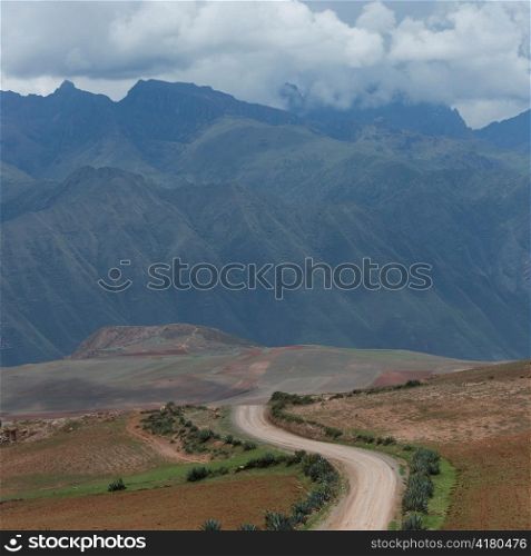 Dirt road passing through a landscape with a mountain range in the background, Sacred Valley, Cusco Region, Peru