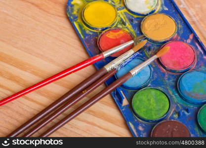 Dirty brushes with paint on a wooden background