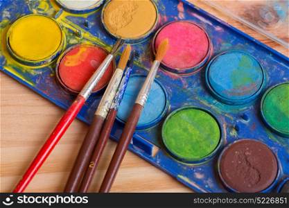 Dirty brushes with paint on a wooden background